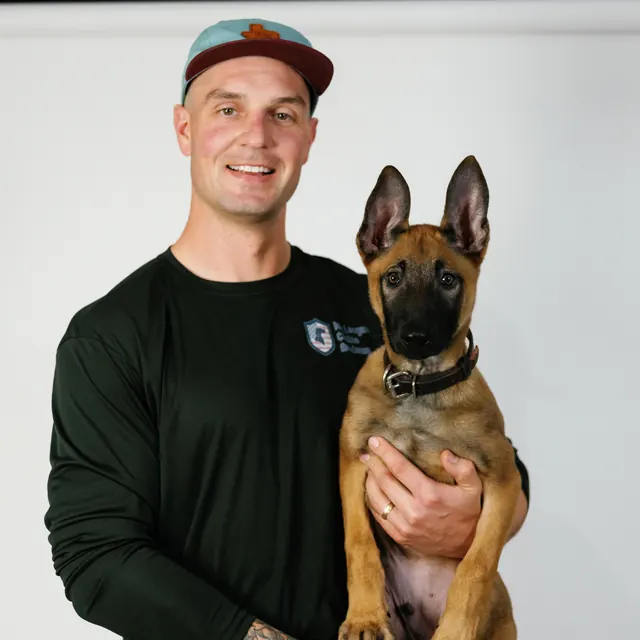 Ivy League Canine Academy trainer with a Malinois puppy